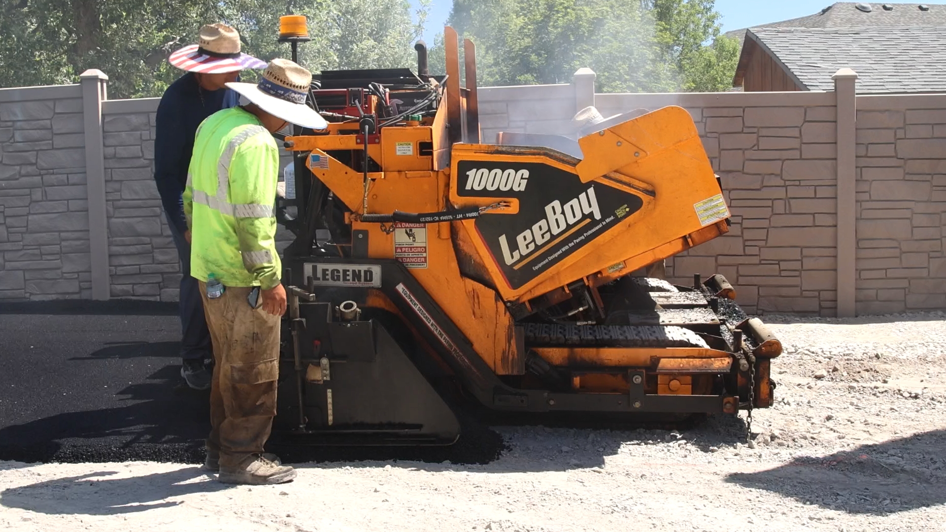 J&C Asphalt branded LeeBoy paver with crew working on a residential driveway