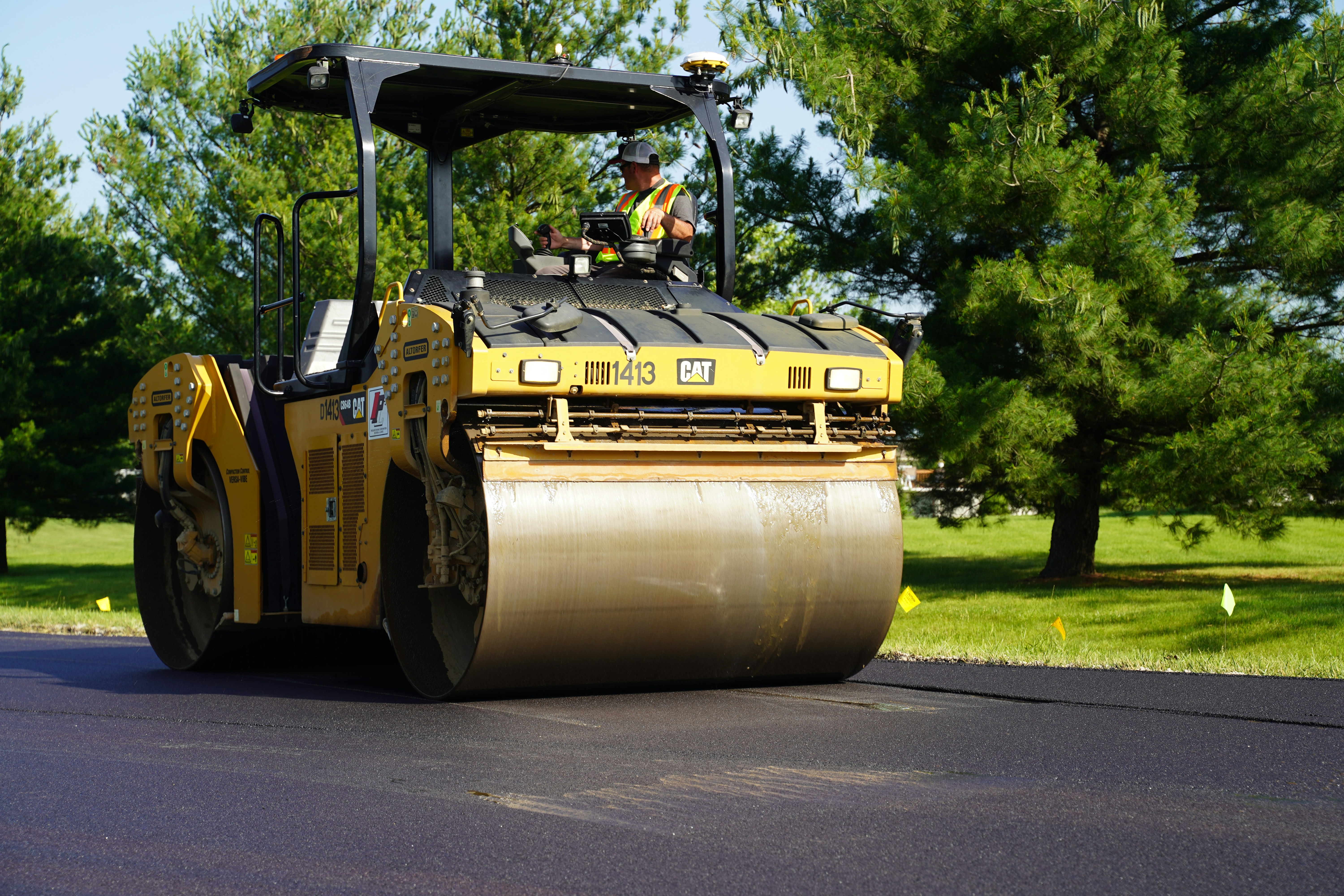Yellow CAT roller compacting fresh asphalt on a commercial parking lot in Utah Valley